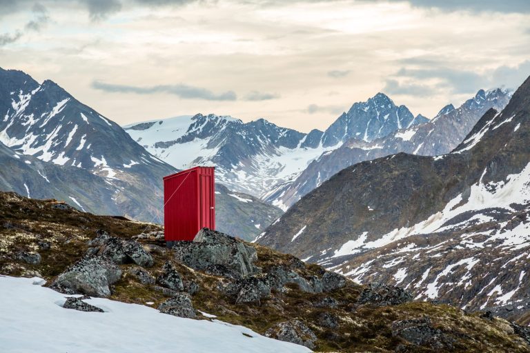 A backcountry hut outhouse with a mountain view in the snowy Alaskan wilderness