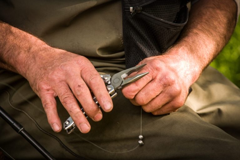 Hands using a multitool pliers to set up a fishing line outdoors