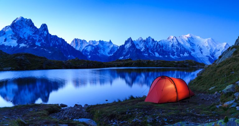 Backpacking tent beside an alpine lake at dusk
