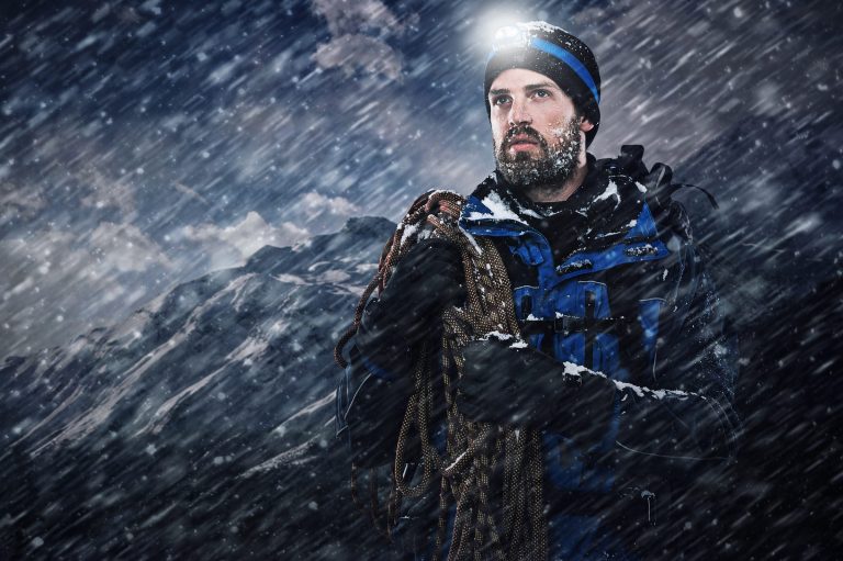Hiker moving across a high exposed snow-covered ridge in thin air