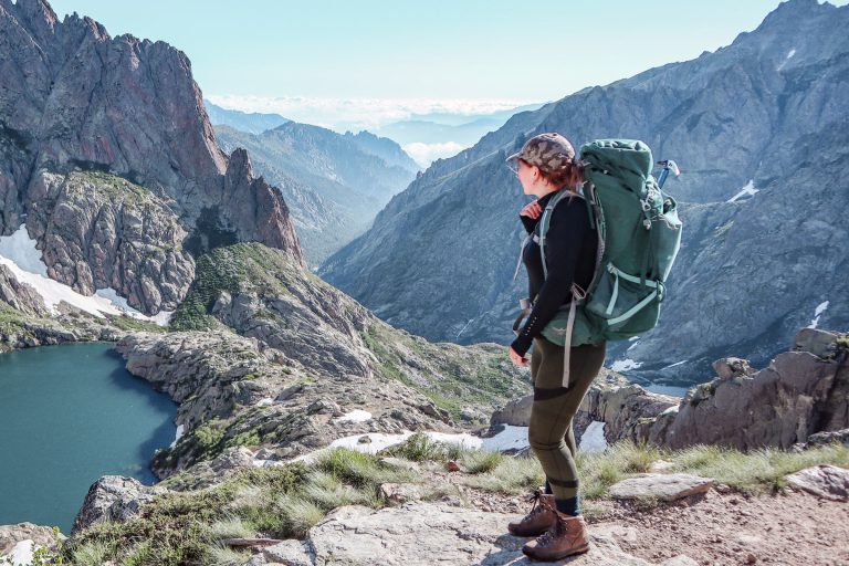 A woman on a mountain trail carrying a loaded multi-day backpack, the hipbelt sitting on her hips