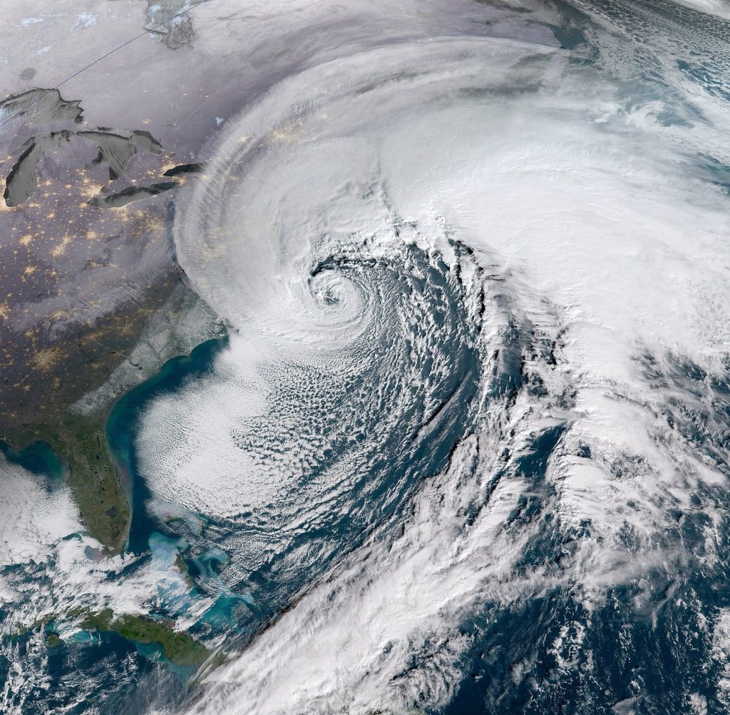 Satellite view of a large comma-shaped storm with a tight spiral centre off the Atlantic coast of the United States, covering the seaboard in cloud